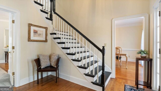 stairs featuring baseboards, wood finished floors, and ornamental molding