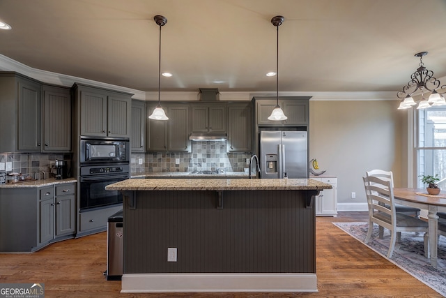 kitchen with crown molding, under cabinet range hood, light stone counters, gray cabinets, and black appliances