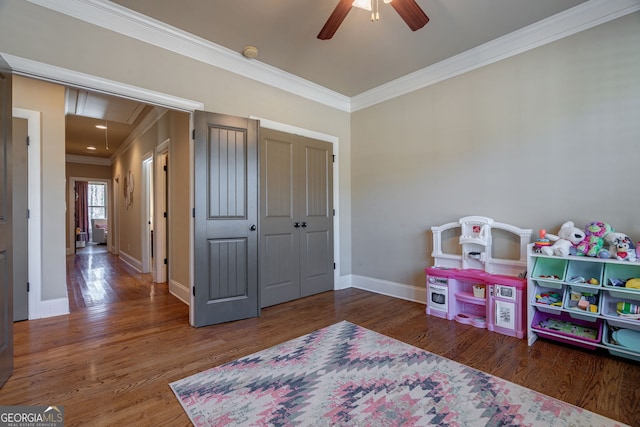 rec room with wood finished floors, baseboards, attic access, ceiling fan, and crown molding