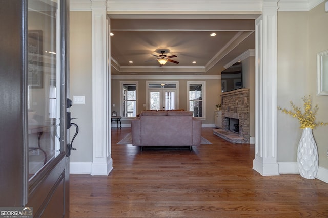 living area featuring a ceiling fan, ornate columns, ornamental molding, dark wood-type flooring, and a raised ceiling