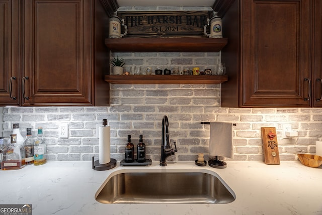 kitchen with open shelves, dark brown cabinets, and a sink