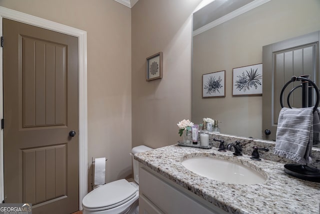 bathroom with toilet, vanity, and crown molding