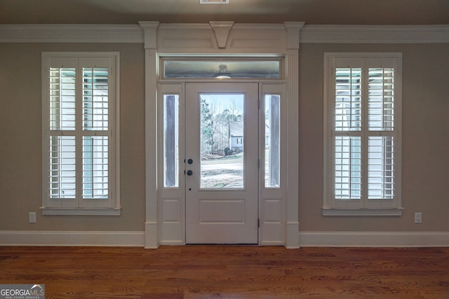 foyer with wood finished floors, a wealth of natural light, and ornamental molding