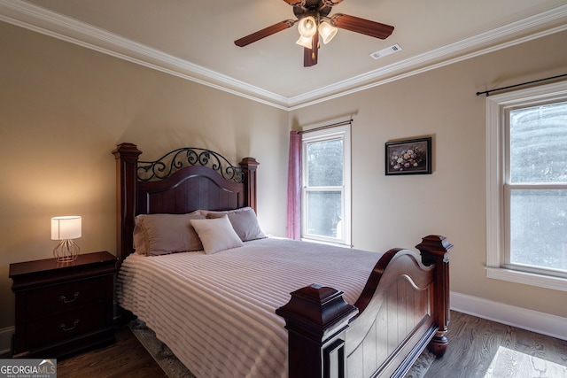 bedroom featuring dark wood finished floors, multiple windows, visible vents, and ornamental molding