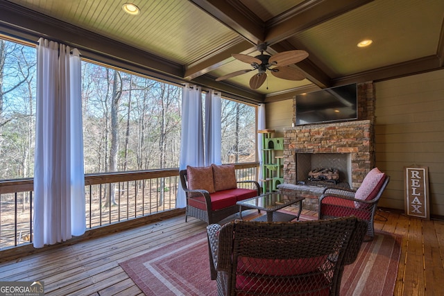 sunroom / solarium featuring beamed ceiling, coffered ceiling, a stone fireplace, and ceiling fan