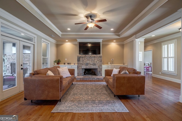 living area featuring ceiling fan, a tray ceiling, and wood finished floors