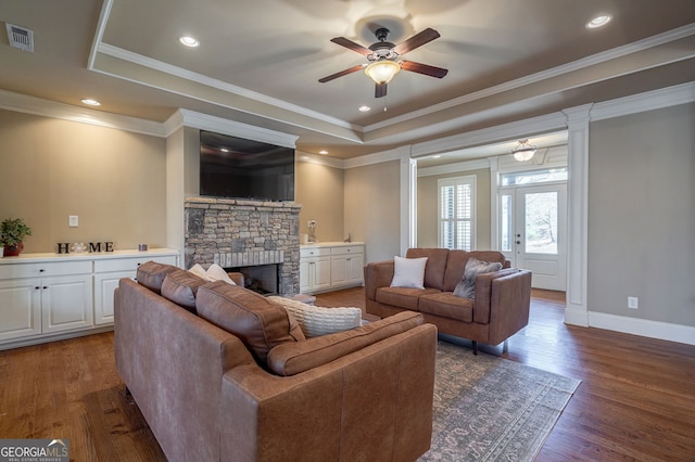 living area with crown molding, ceiling fan, a tray ceiling, a fireplace, and wood finished floors