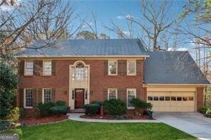 colonial-style house featuring a front lawn, a garage, and driveway