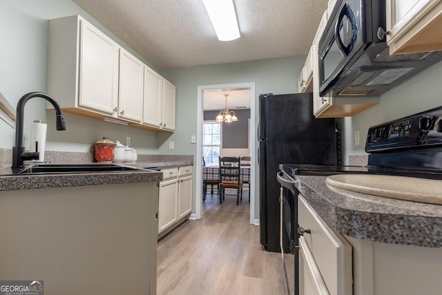 kitchen featuring black appliances, a sink, a textured ceiling, white cabinets, and light wood finished floors