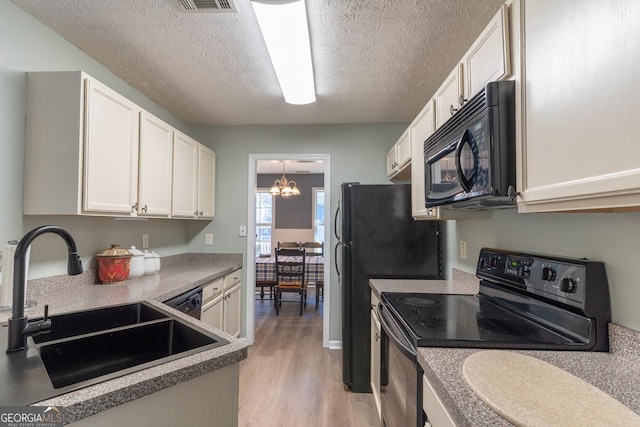 kitchen with white cabinetry, black appliances, light wood-style flooring, and a sink