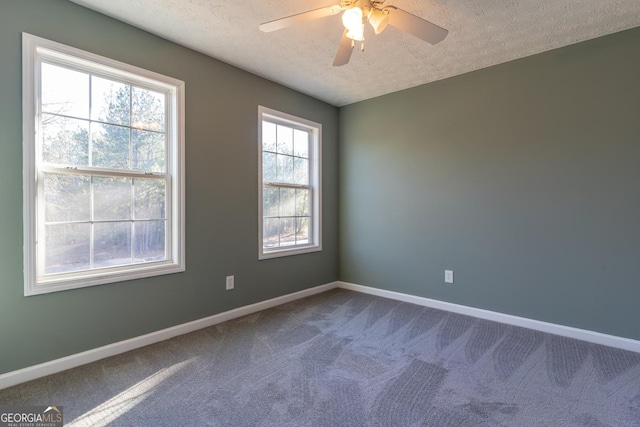 empty room with ceiling fan, baseboards, dark colored carpet, and a textured ceiling