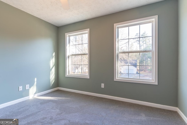 empty room featuring baseboards, carpet, ceiling fan, and a textured ceiling