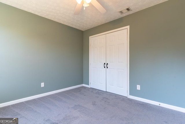 unfurnished bedroom featuring carpet, baseboards, visible vents, a closet, and a textured ceiling