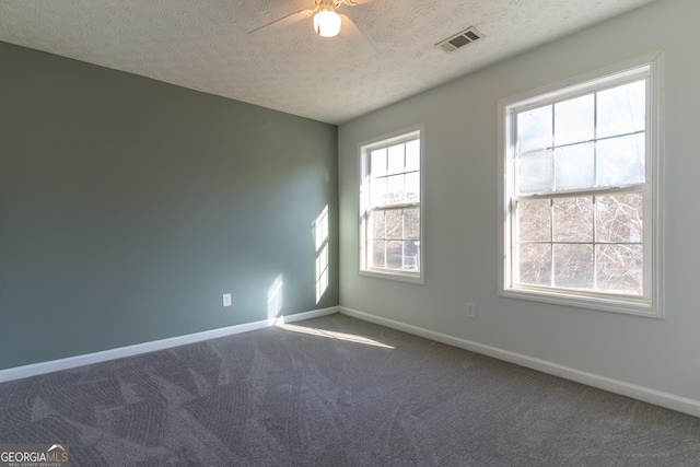 empty room with visible vents, carpet floors, baseboards, and ceiling fan