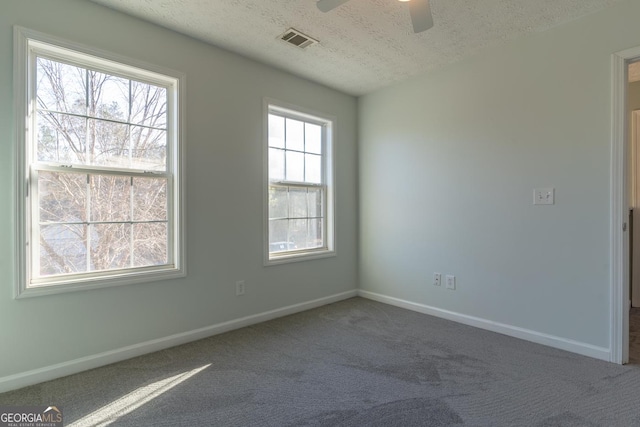 carpeted spare room with baseboards, visible vents, a textured ceiling, and ceiling fan