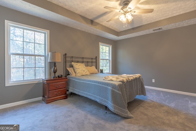 carpeted bedroom featuring baseboards, visible vents, ceiling fan, a textured ceiling, and a raised ceiling