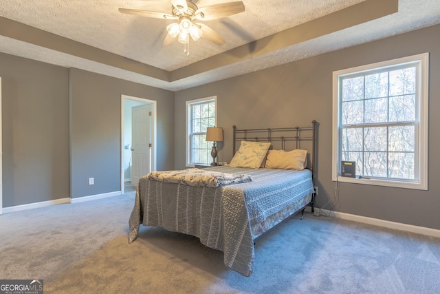 bedroom with a tray ceiling, carpet floors, a textured ceiling, and baseboards