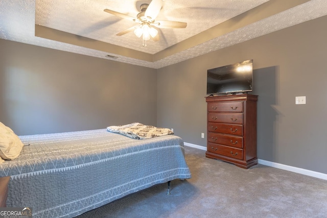 bedroom with a raised ceiling, carpet flooring, baseboards, and a textured ceiling