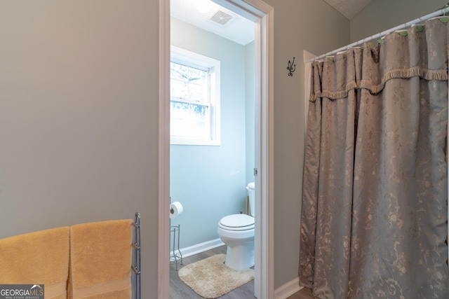 bathroom featuring curtained shower, toilet, baseboards, and visible vents