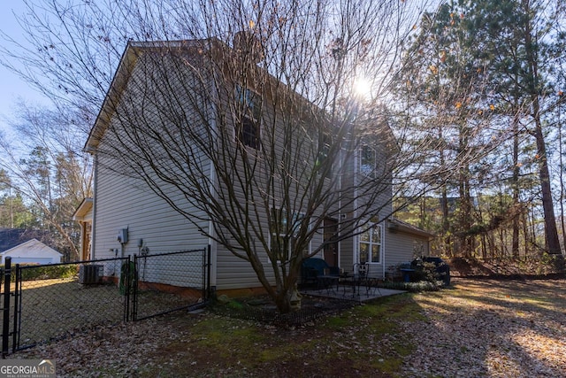 view of home's exterior featuring central AC unit, a gate, a patio area, and fence