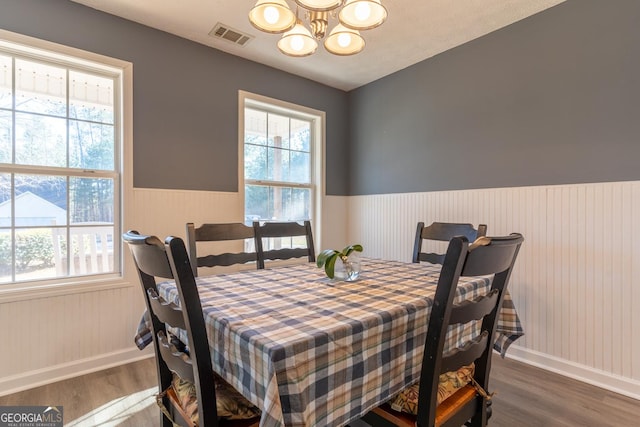 dining room with visible vents, a notable chandelier, wood finished floors, and wainscoting