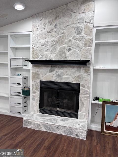 interior details featuring a stone fireplace and wood finished floors