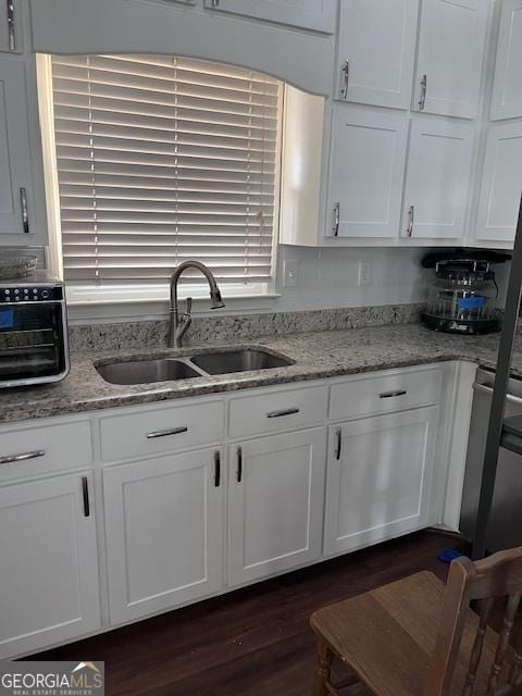 kitchen featuring white cabinets, dark wood-style floors, light stone countertops, and a sink