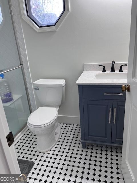 full bathroom with vanity, baseboards, a skylight, a stall shower, and toilet