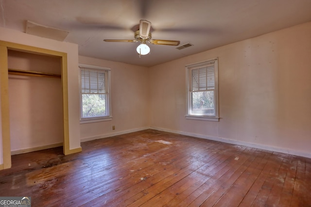 unfurnished bedroom featuring visible vents, multiple windows, baseboards, and hardwood / wood-style floors