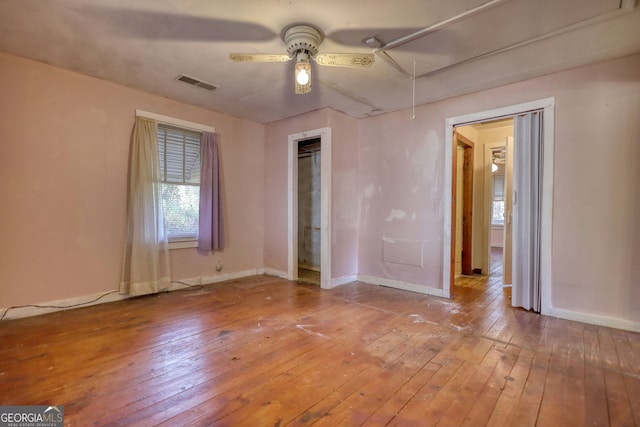 unfurnished bedroom featuring a ceiling fan, baseboards, visible vents, attic access, and wood-type flooring