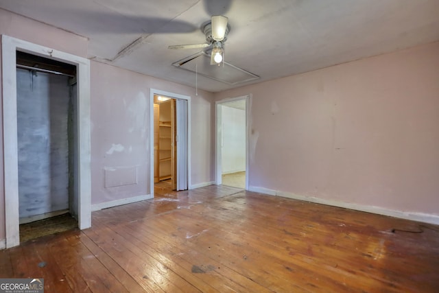 unfurnished bedroom featuring attic access, hardwood / wood-style flooring, baseboards, and ceiling fan