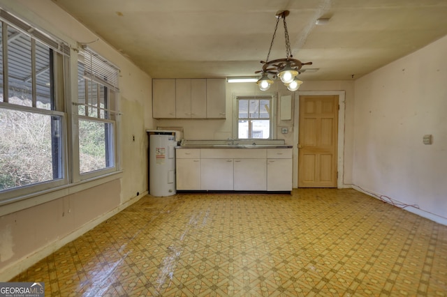 kitchen featuring electric water heater, baseboards, light floors, white cabinetry, and a sink