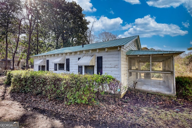 view of property exterior with metal roof and a sunroom