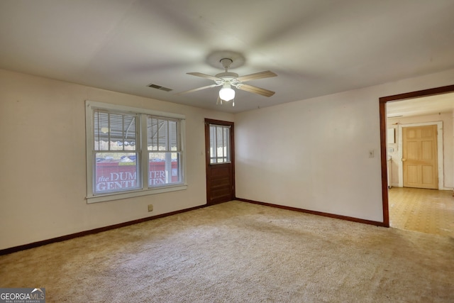 carpeted spare room with visible vents, baseboards, and ceiling fan