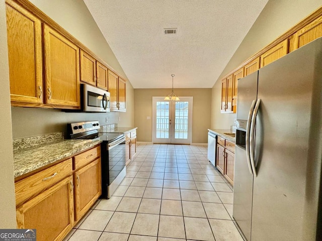 kitchen with stainless steel appliances, french doors, brown cabinetry, light tile patterned floors, and lofted ceiling