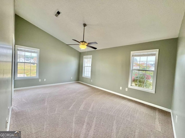 empty room with a ceiling fan, visible vents, baseboards, vaulted ceiling, and carpet flooring