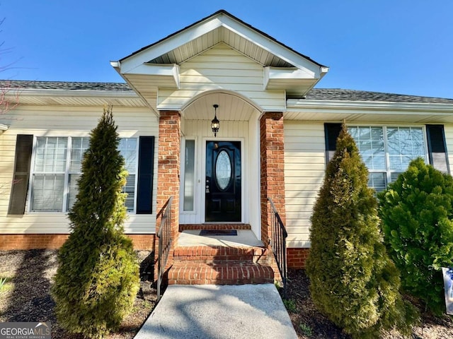 doorway to property with a shingled roof