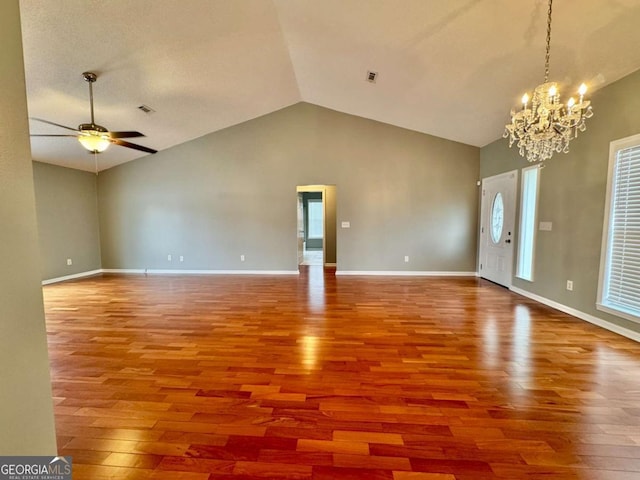 interior space featuring visible vents, baseboards, lofted ceiling, ceiling fan with notable chandelier, and wood finished floors