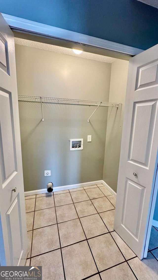 clothes washing area featuring baseboards, washer hookup, laundry area, and tile patterned flooring