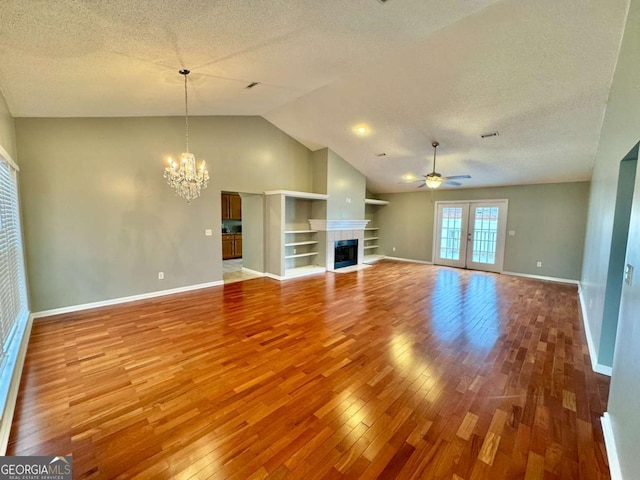 unfurnished living room with wood-type flooring, a textured ceiling, a fireplace, and ceiling fan with notable chandelier