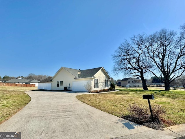 view of side of home with a garage, a lawn, driveway, and fence