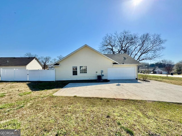 exterior space featuring a yard, fence, a garage, and driveway