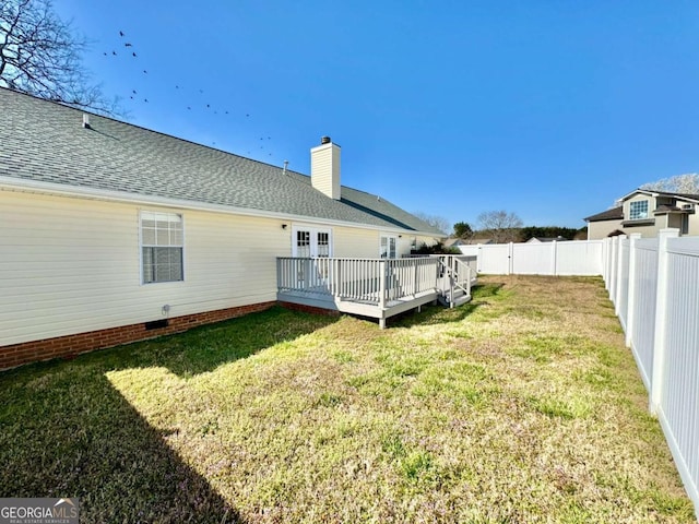 rear view of house featuring a fenced backyard, a yard, roof with shingles, a wooden deck, and a chimney