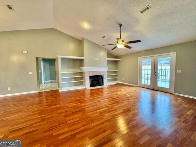 unfurnished living room featuring visible vents, built in features, a textured ceiling, wood finished floors, and ceiling fan