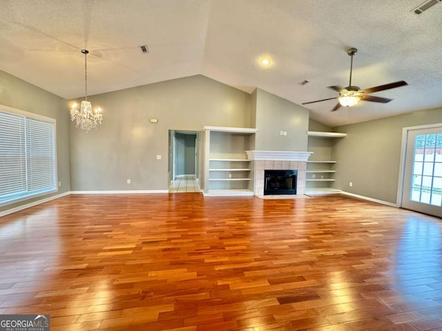 unfurnished living room featuring visible vents, ceiling fan with notable chandelier, a textured ceiling, and wood-type flooring