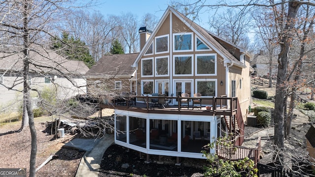 rear view of property featuring french doors, stairway, a sunroom, a wooden deck, and a chimney