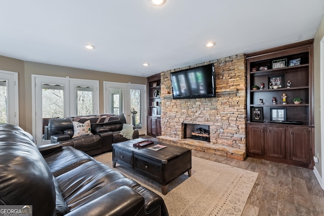 living room with light wood finished floors, recessed lighting, a fireplace, and french doors