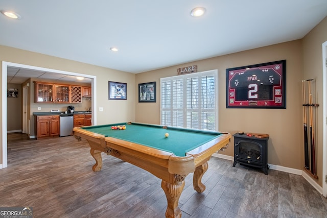 game room featuring baseboards, light wood-type flooring, indoor wet bar, recessed lighting, and a wood stove