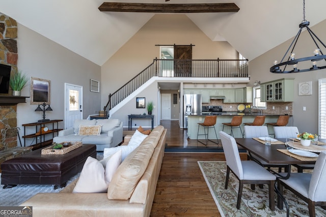 living room featuring an inviting chandelier, dark wood-type flooring, stairway, and lofted ceiling with beams