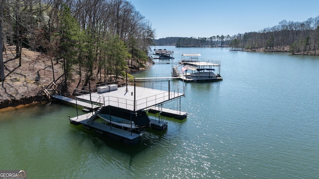 view of dock featuring a view of trees, a water view, and boat lift